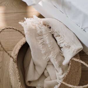 A wicker basket with a soft fringed white blanket adds warmth and texture to a modern bedroom.